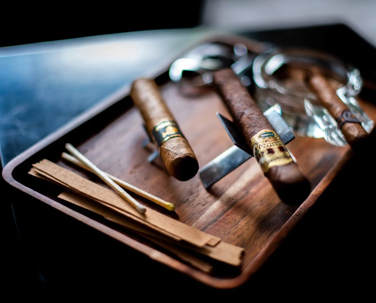 Cigars and a cutter laid out on a wooden board at Poison Ivy
