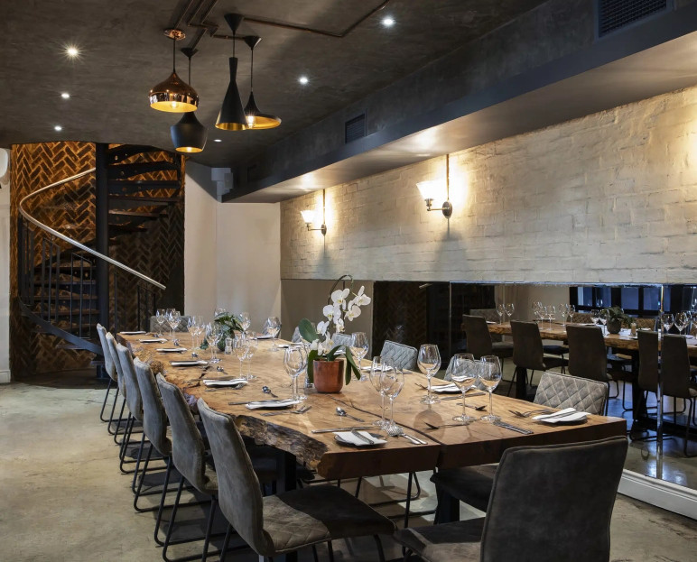 A long private dining table set under pendant lights