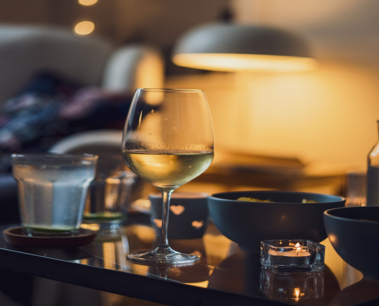 A glass of white wine and water on a table set for in-room dining